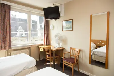 a hotel room with a desk and a bed and a mirror at Hotel Bristol Internationaal in Mortsel