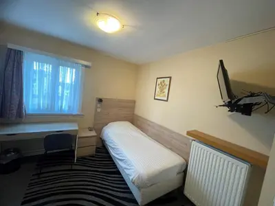 a bedroom with a bed and a desk and a television at Hotel Bristol Internationaal in Mortsel