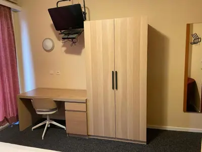 a wooden cabinet with a desk and a television at Hotel Bristol Internationaal in Mortsel