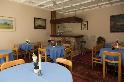 a restaurant with blue tables and chairs and a fireplace at Hotel Bristol Internationaal in Mortsel