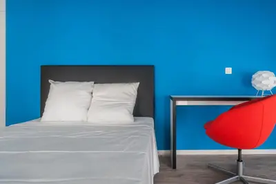 a bedroom with a bed and a red chair at Ooostel2.be Leuven in Leuven