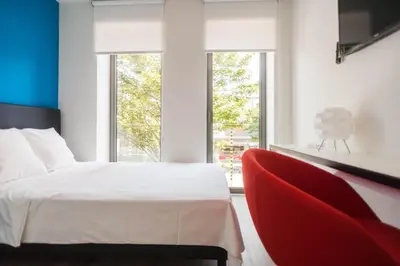 a bedroom with a bed and a red chair at Ooostel2.be Leuven in Leuven
