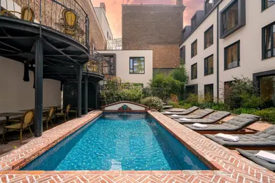 a swimming pool with chaise lounge chairs next to a building at Latroupe Hotel Jardin Secret in Brussels