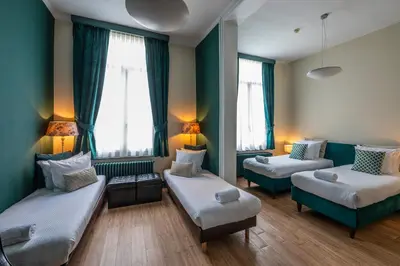 a room with two beds and two windows at Hotel Onderbergen in Ghent