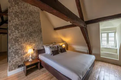 a bedroom with a bed and a stone wall at Hotel Onderbergen in Ghent