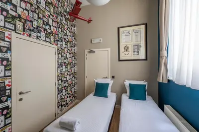 two beds in a room with a wall of pictures at Hotel Onderbergen in Ghent