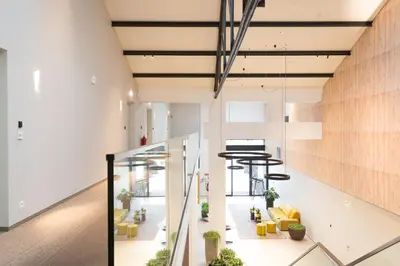an office lobby with yellow chairs and tables at Hotel Den Berg in Londerzeel