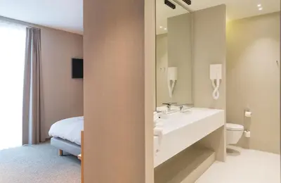 a bathroom with a sink and a toilet and a mirror at Hotel Den Berg in Londerzeel