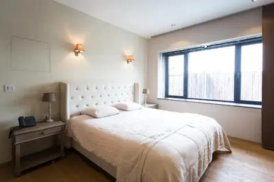a bedroom with a white bed and a large window at Hotel Den Berg in Londerzeel