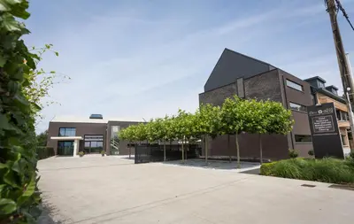 a brick building with trees in front of it at Hotel Den Berg in Londerzeel