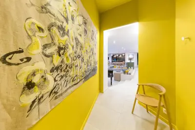 a yellow hallway with a chair and a painting on the wall at Wok Rooms in Brussels