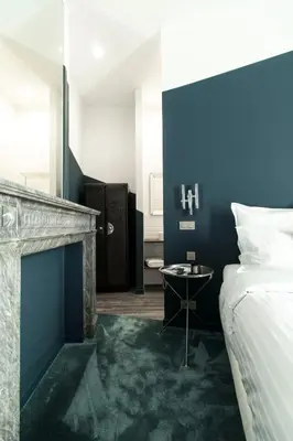 a bedroom with a bed and a table next to a fireplace at Wok Rooms in Brussels