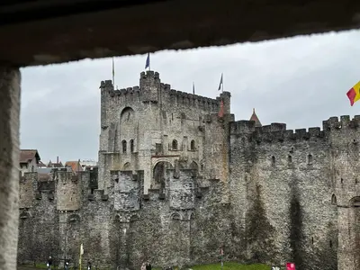 a large stone castle with two flags on top at De Waterzooi Suites in Ghent