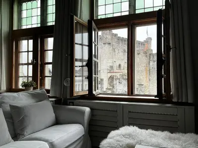 a living room with a couch and a large window at De Waterzooi Suites in Ghent