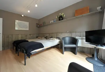 a bedroom with a bed and a chair and a television at aan de vaart in Mechelen