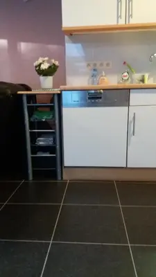 a kitchen with white cabinets and a tile floor at jutta in Mechelen