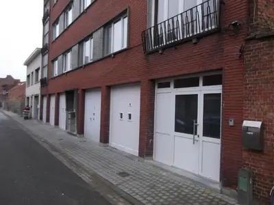 a brick building with white garage doors on a street at jutta in Mechelen