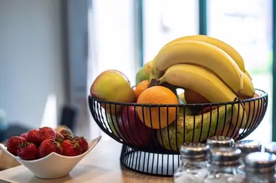 a bowl of fruit with bananas oranges and strawberries at Hobbit Hotel Mechelen in Mechelen