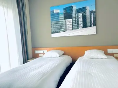 two beds in a room with a picture of a city at Hobbit Hotel Mechelen in Mechelen