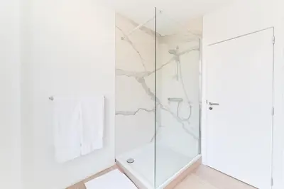 a white bathroom with a shower and a glass door at B&B X2Brussels in Brussels