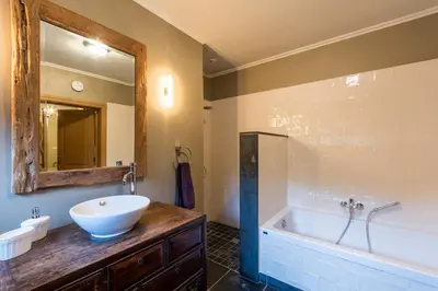 a bathroom with a sink and a tub and a mirror at Chez Maintje in Bassevelde