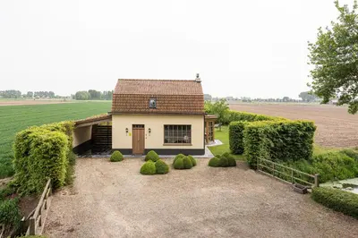 a house with a large yard in front of a field at Chez Maintje in Bassevelde