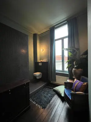 a bathroom with a toilet and a window and a couch at Guesthouse Nights by Morpheus in Antwerp