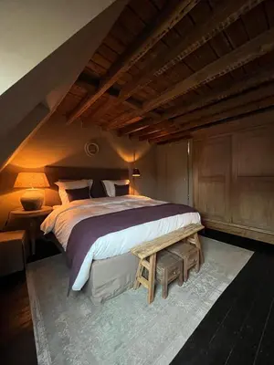 a bedroom with a large bed and a bench at Guesthouse Nights by Morpheus in Antwerp