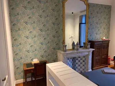 a room with a fireplace and a mirror and a bed at Albert Molière in Brussels