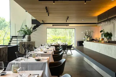 a restaurant with white tables and chairs and a large window at De Koolputten in Waasmunster