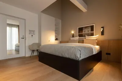 a bedroom with a large bed and a chair at De Koolputten in Waasmunster