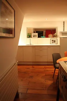 a kitchen with white cabinets and a wooden floor at De Buitenmuur - Vintage Suite & Bohemian Loft, elk met Privé-ingang en Jacuzzi in Turnhout