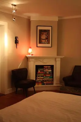 a bedroom with a fireplace with two chairs and books at De Buitenmuur - Vintage Suite & Bohemian Loft, elk met Privé-ingang en Jacuzzi in Turnhout