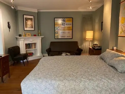 a bedroom with a bed and a chair and a fireplace at De Buitenmuur - Vintage Suite & Bohemian Loft, elk met Privé-ingang en Jacuzzi in Turnhout