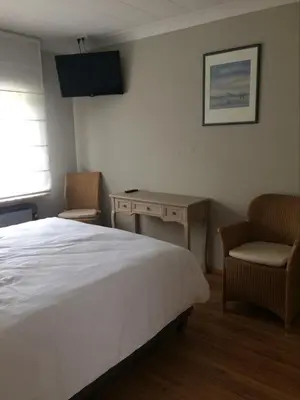a bedroom with a bed and two chairs and a desk at Le Lendemain in Lovendegem
