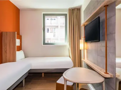 a hotel room with two beds and a tv at ibis budget Gent Centrum Dampoort in Ghent
