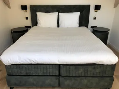 a large bed in a room with two tables at Hof Van Volmersele - Luxury B&B in Kampenhout
