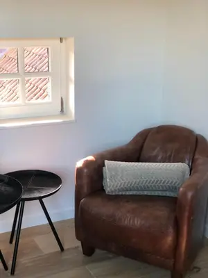 a brown leather chair sitting in a room with a window at Hof Van Volmersele - Luxury B&B in Kampenhout
