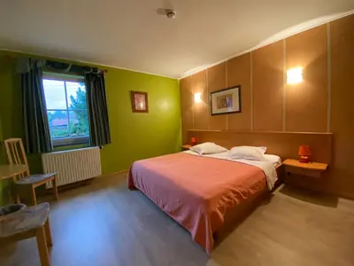 a bedroom with a bed with green walls and a window at Hotel In Den Hoek in Tielt
