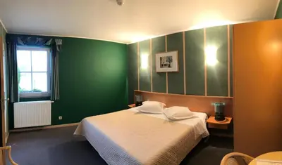 a bedroom with green walls and a white bed at Hotel In Den Hoek in Tielt