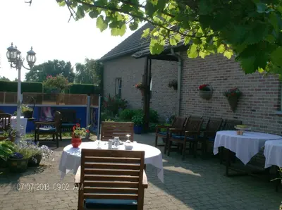 a patio with tables and chairs and a building at Hotel In Den Hoek in Tielt
