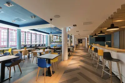a restaurant with tables and chairs and windows at Hampton By Hilton Antwerp Central Station in Antwerp
