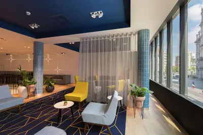 a lobby with chairs and tables and windows at Hampton By Hilton Antwerp Central Station in Antwerp