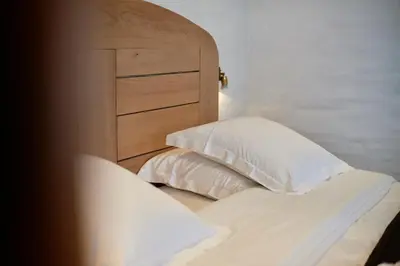 a bed with a wooden headboard and two pillows at Hotel Colvenier in Antwerp