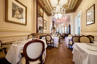 a restaurant with white tables and chairs and a chandelier at Hotel Colvenier in Antwerp