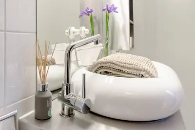 a white sink in a bathroom with purple flowers at BXLROOM Guesthouse in Brussels