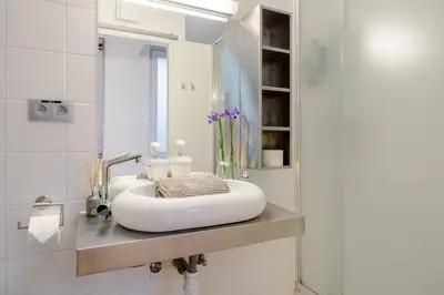 a white bathroom with a sink and a mirror at BXLROOM Guesthouse in Brussels