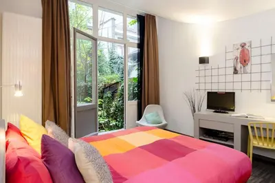 a bedroom with a colorful bed and a window at BXLROOM Guesthouse in Brussels