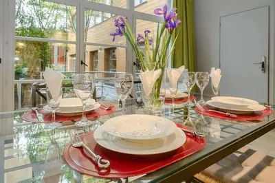 a glass table with plates and glasses and flowers on it at BXLROOM Guesthouse in Brussels