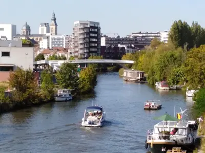 a group of boats in a river with a bridge at Scheldepunt in Ghent